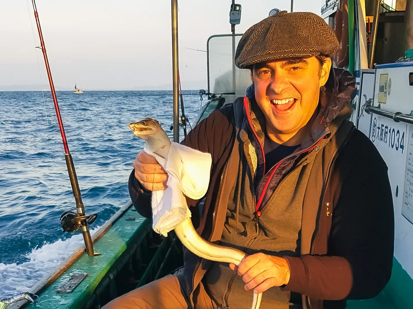 Chris P King catching a hamo fish on a boat in Osaka Bay